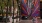 people sit beside high building with large, colorful mural